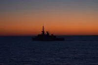 La frégate Aconit à contre-jour sur le soleil couchant